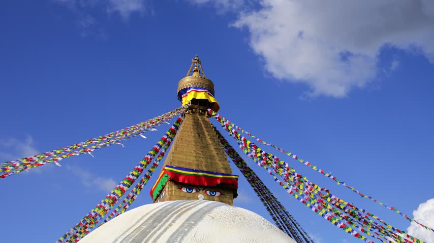 Namche Bazar, Nepal - 05.05.2026: Boudhanath Stupa in Kathmandu, Nepal, one of the most significant Buddhist monuments in the country and an important pilgrimage destination. The massive white dome, golden pinnacle, colorful prayer flags, and surrounding religious architecture create a distinctive cultural landmark in the heart of the Kathmandu Valley. Devotees and visitors move around the sacred structure, reflecting centuries of Buddhist tradition, meditation, worship, and spiritual practice. Suitable for travel documentaries, tourism campaigns, cultural productions, educational films, religious content, and cinematic destination footage. The scene showcases Nepalese heritage, Tibetan Buddhist influence, traditional architecture, pilgrimage culture, and the enduring spiritual atmosphere of this iconic Asian landmark.
