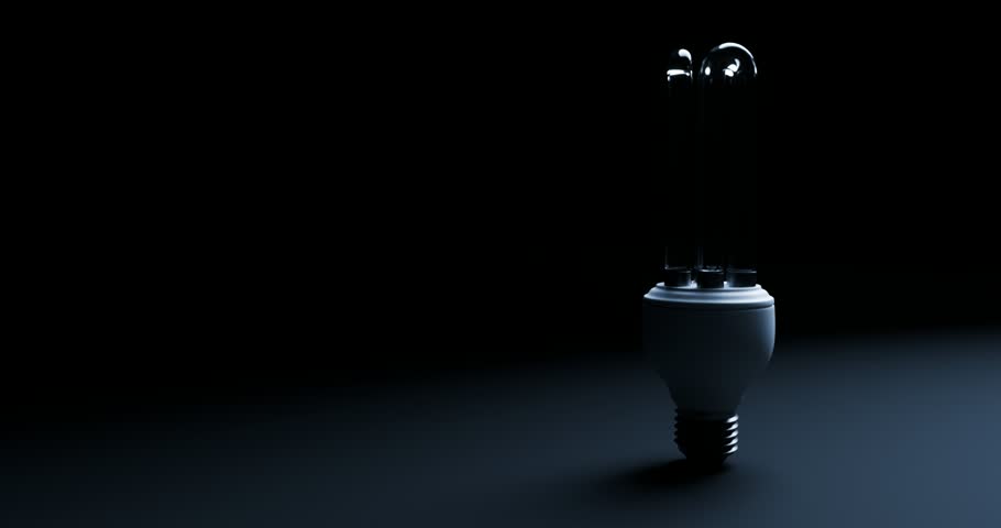 Energy saving cfl light bulb turning on and flickering in dark background with copy space