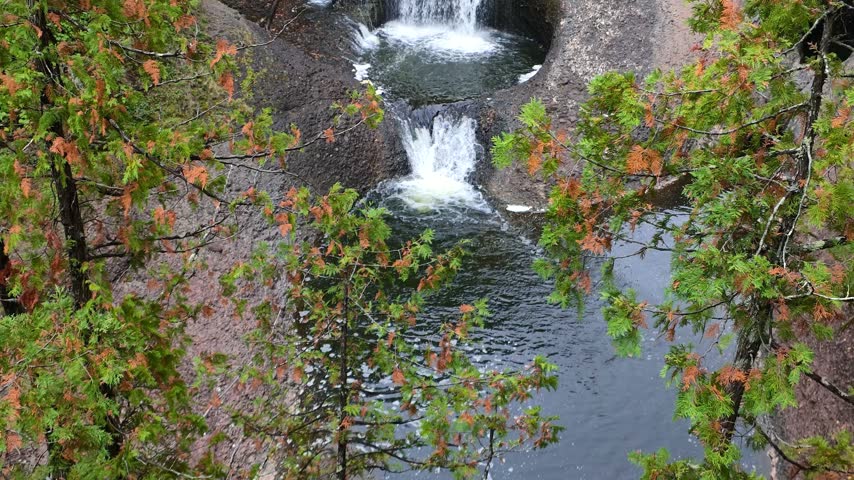 Water flowing down a series of small waterfalls through potholes carved into the rock at Black river national forest in Michigan.