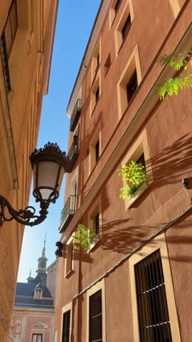 Historic buildings with a vintage streetlamp standing in a narrow alley in Madrid, Spain, under a clear blue sky on a sunny day in the city center during the fall or summer season