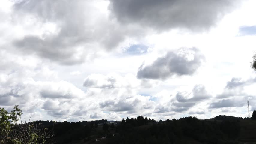 Time lapse of storm clouds moving over forested hills