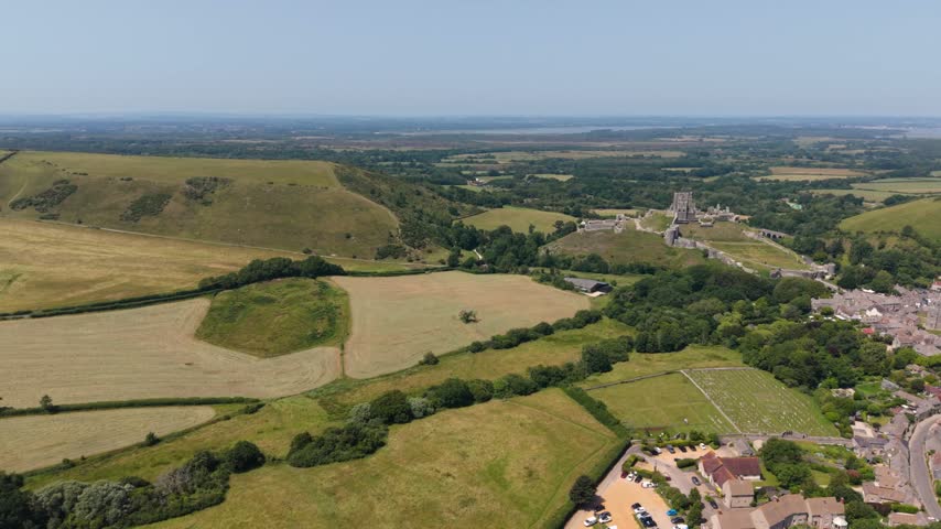 Corfe Castle Isle of Purbeck Dorset, England, high,slow,backwards drone footage of the Isle of Purbeck with the castle and village and views across to Poole harbour on bright sunny day