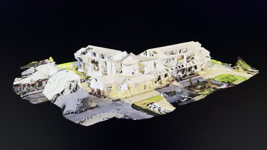 Coloured 3D d model of a mixed use corner building rotates in space, revealing height, roads and surrounding green areas.
