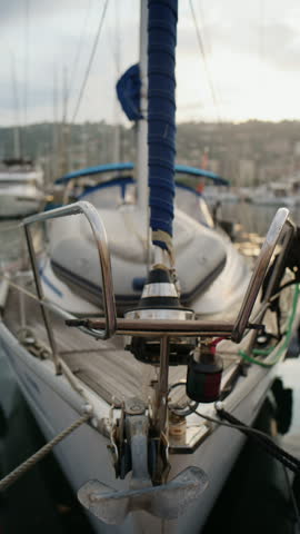 Close up view of a sailboat stern with blue wrapped rigging, anchor, deck hardware, and marina reflections at Port Vauban in Antibes, France