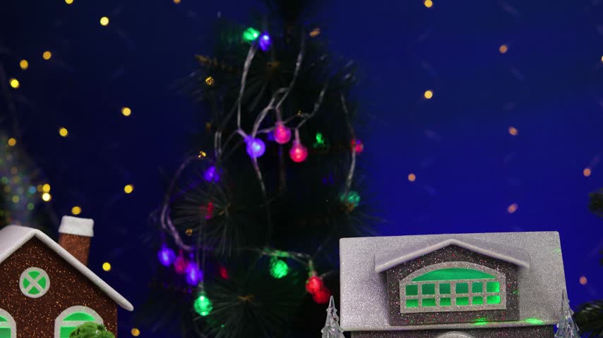 A snowman on a sled with letters in the foreground of a Christmas village