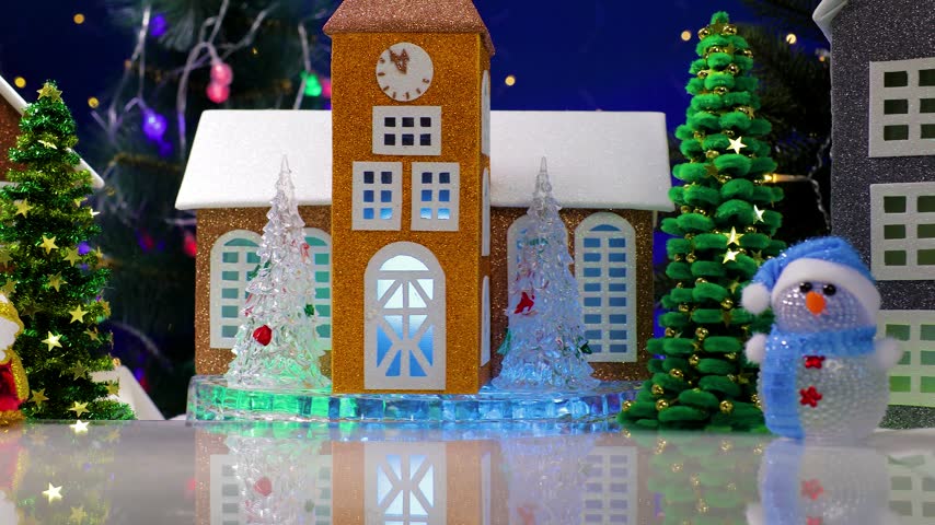 An orange car pulls up to two snowmen in the center of the Christmas village