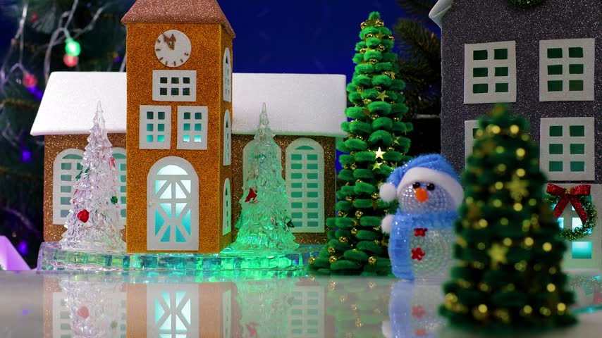 A yellow car pulls up to a red house in the center of the Christmas village