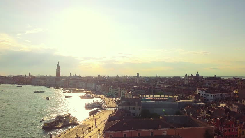 Drone advances over Venice with bright hazy sunlight over the water, Italy