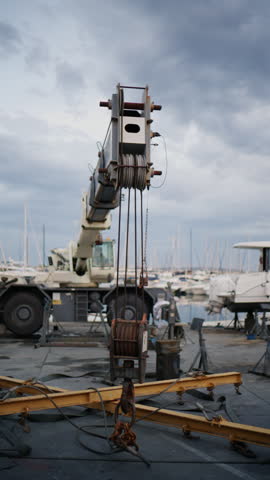 Close up of a large boatyard crane and pulley system at Port Vauban Marina in Antibes, France, with yachts and sailboats blurred in the background