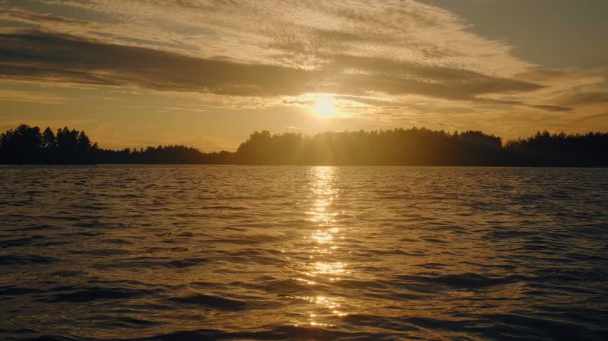 Serene sunset over a calm lake in Finland, golden sunlight reflecting on rippling water, silhouetted tree line, dramatic sky with textured clouds, gentle landscape.