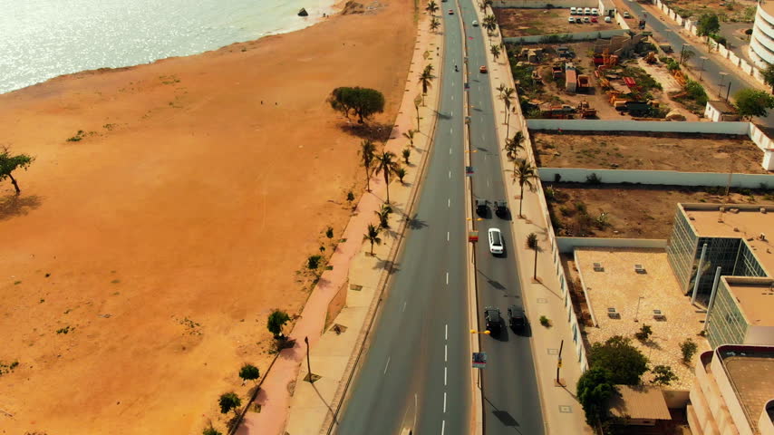 Low aerial view of cars driving along a beachfront road in Morocco