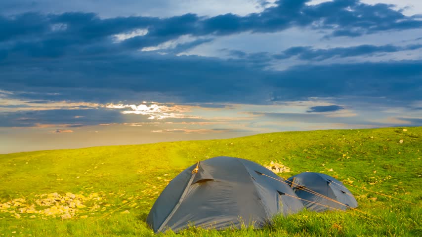 touristic tent among green hills at the sunset, natural travel camping time lapse scene