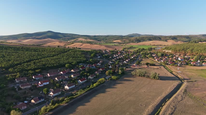 Aerial view of Rákóczibánya village amid cultivated fields, orchards and forested hills in Hungary