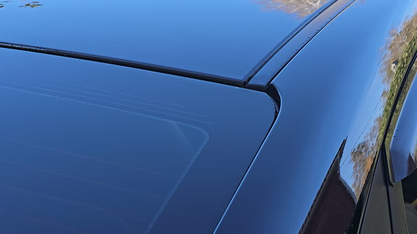 Blue car roof gleams under sun. Smooth surface reflects trees and sky. No people, no animals, no plants. Ideal for auto, luxury, or automotive design projects