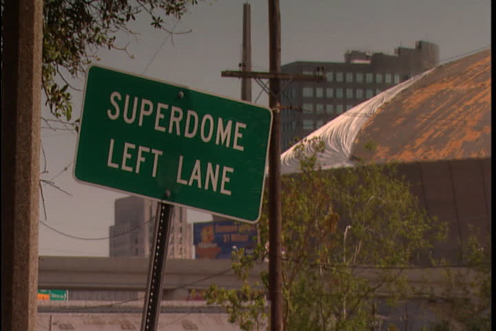Street sign for Superdome and damaged roof of Superdome in background in New Orleans after Hurricane Katrina (October 2005).