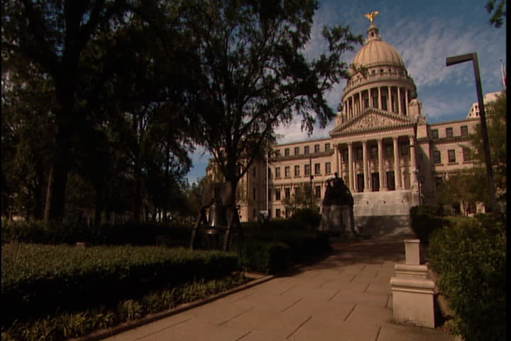 Mississippi State Capitol building framed by green leafy branches in Jackson, Mississippi.