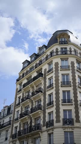 Slow camera movement showing typical Parisian residential architecture with stone facade and black iron balconies.