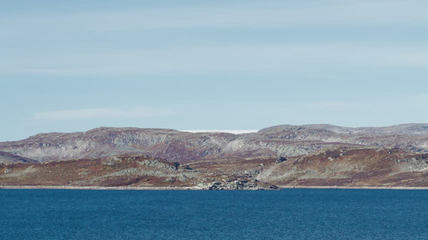 Still deep water fills a high plateau reservoir beneath brown rocky uplands and a pale sky in the Norwegian nature woods forest.
