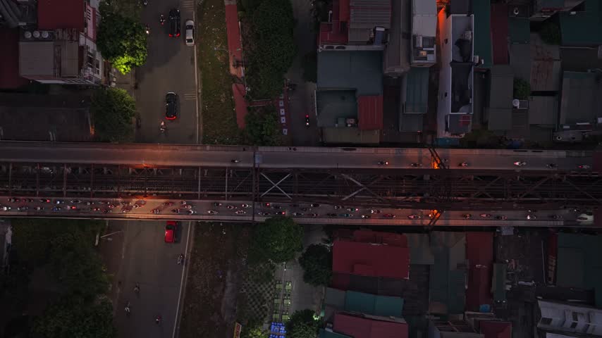 Aerial top down view showing heavy motorbike and car traffic on the historic long bien bridge and adjacent roads in hanoi, vietnam, at night