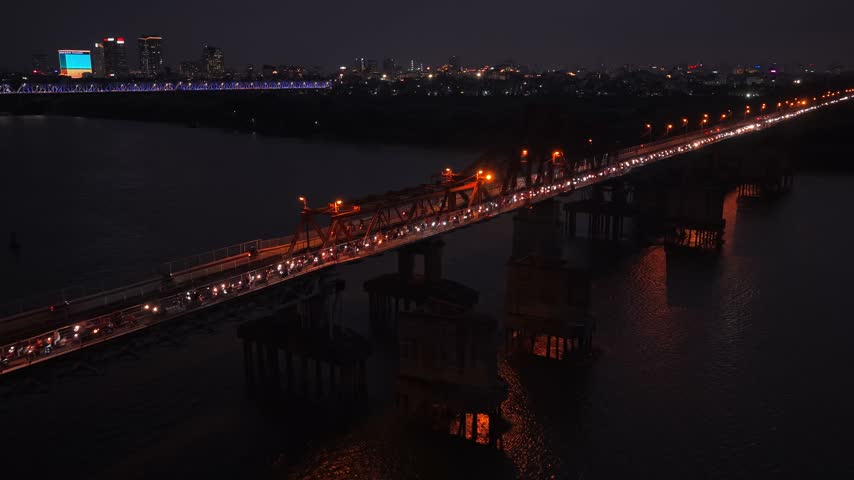 Aerial view of heavy evening traffic with motorbikes and cars crossing the historic long bien bridge over the red river in hanoi, vietnam