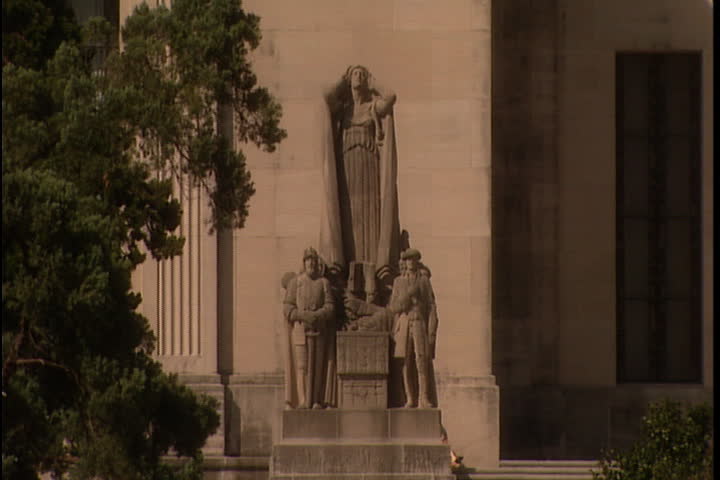 Camera tilts up from statue of The Pioneers by Lorado Taft to windows in the Art Deco tower in Baton Rouge, Louisiana.