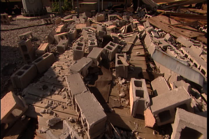 Pile of cinderblock rubble on ground, tilt up to antenna tower against blue sky in New Orleans after Hurricane Katrina (October 2005).