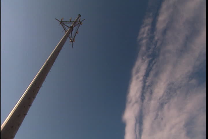 Towering antenna against blue sky, tilt down to broken up building and rubble pile in New Orleans after Hurricane Katrina (October 2005).