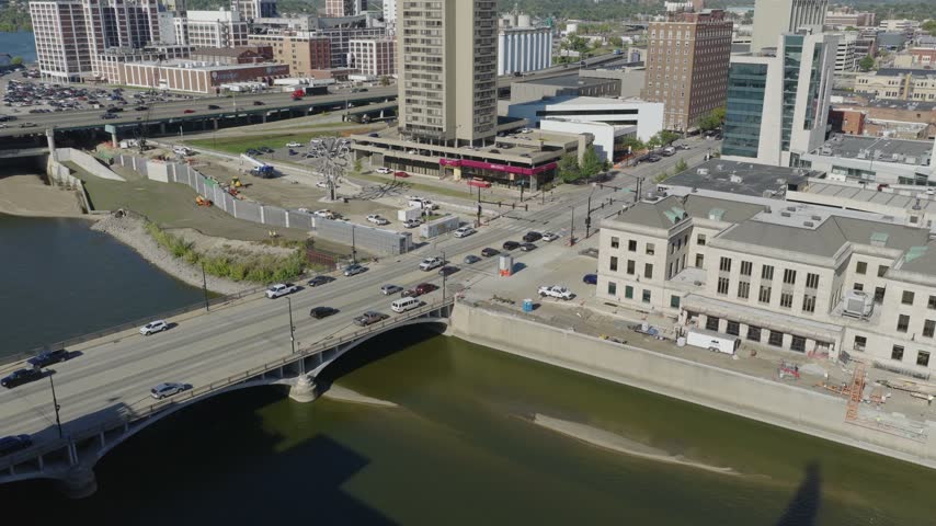 Downtown buildings and landscaped riverfront in Cedar Rapids, Iowa, aerial pullback ascend reveals glistening Veterans Memorial Building