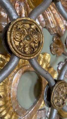 Close up shot of antique metal lattice with ornate golden brass medallions, floral decorations inside historic building. Decorative vintage architectural metalwork, classical indoor design background