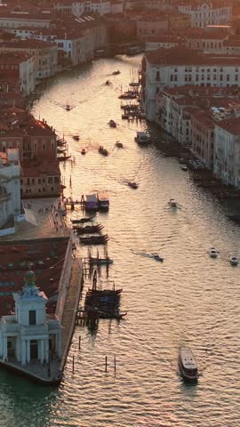 Breathtaking aerial view of Venice canals with busy boat traffic at sunset golden hour, showcasing historic architecture and shimmering water.