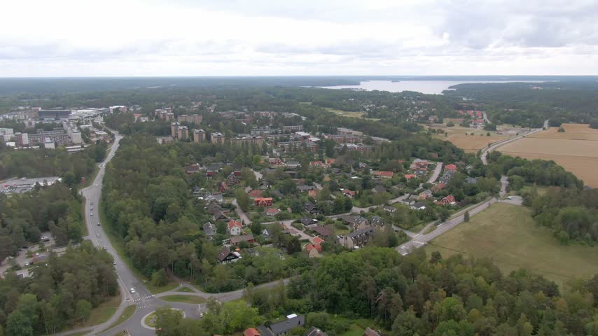 Wide aerial of suburb, forest and golden fields, Uppsala, Sweden, overcast day.