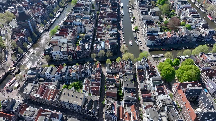 Aerial view of Amsterdam, Netherlands, showcasing historic buildings, canals, waterways and the vibrant cityscape, captured from above on a beautiful day.