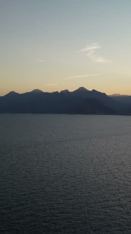 Sunset over Antalya Bay, Turkey, with mountain silhouettes, a golden reflection on the Mediterranean Sea and the coastline fading into evening light.