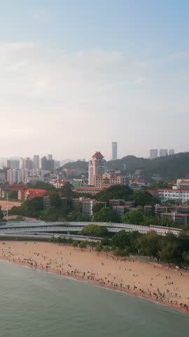 Stunning aerial view of Xiamen University, showcasing its beautiful coastal location with a sandy beach, lush greenery, modern buildings, and a serene lake, offering a glimpse into a vibrant academic and scenic environment.