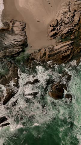 Beautiful aerial view of stones meeting the waves from the ocean in Campsbay Capetown, South Africa