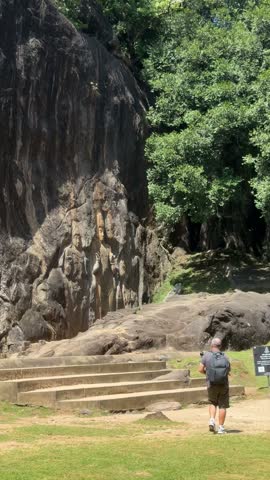 Pan shot of giant ancient rock carved Buddha statue and figures at Buduruwagala temple in Sri Lanka