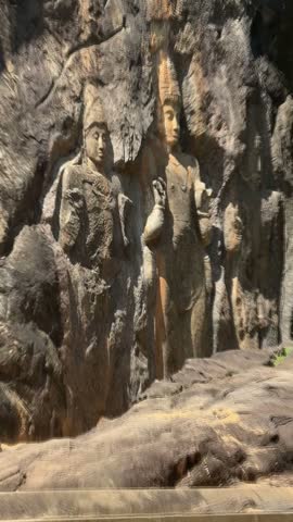 Pan shot of giant ancient rock carved Buddha statue and figures at Buduruwagala temple in Sri Lanka