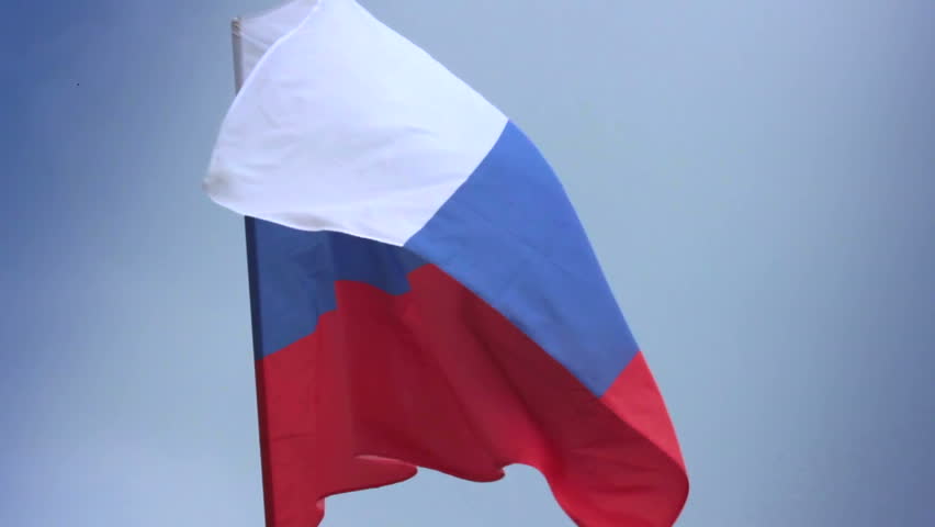 Russian national flag waving on flagpole in blue sky. Russia