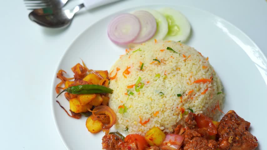 Vegetable Fried Rice with Spicy Chicken and Fresh Garnish on White Plate.