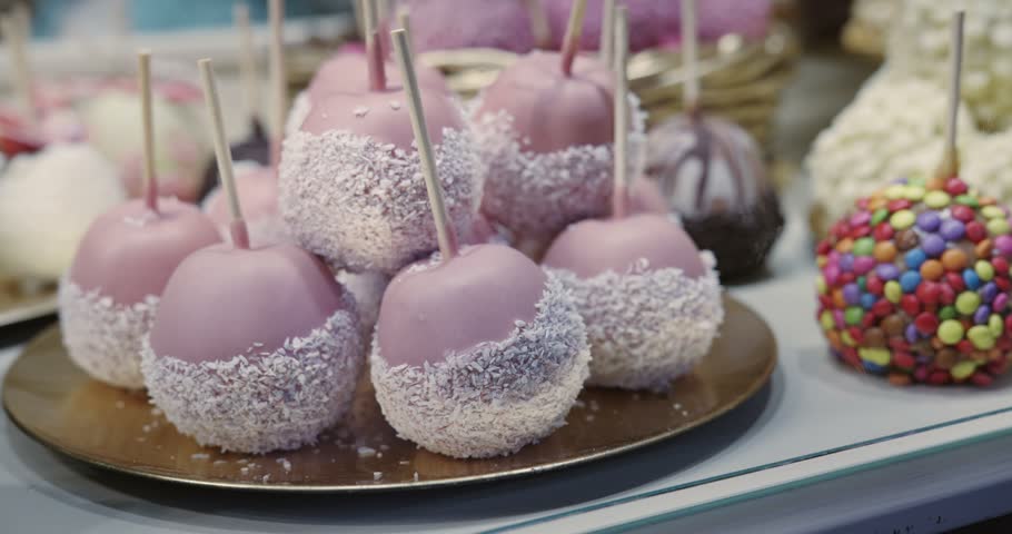 A display of decorated candied apples assorted desserts, including a chocolate covered strawberry, a chocolate covered apple at Christmas market