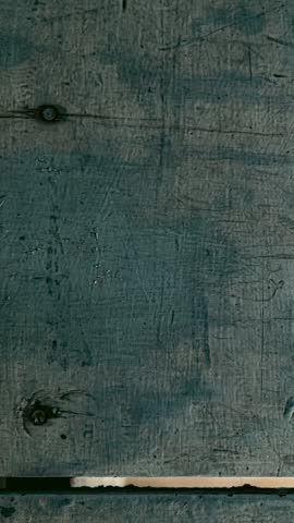 Close-up of a weathered teal painted wood surface with visible scratches and grain patterns, separated by a horizontal white line. Background texture.