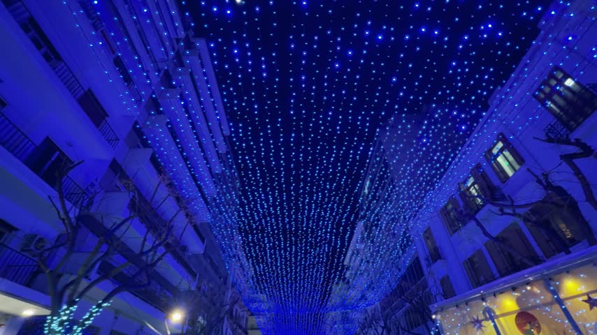 Blue Christmas lights illuminate Agia Sofias Street in Thessaloniki, Greece at night. The festive decorations create a magical urban atmosphere, capturing authentic holiday spirit in the city center.