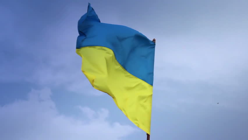 Ukrainian national flag waving on flagpole in blue sky. Ukraine
