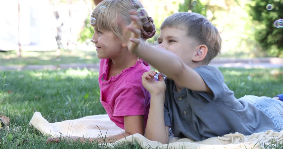 Cute little girl and boy playing with soap bubbles outdoors