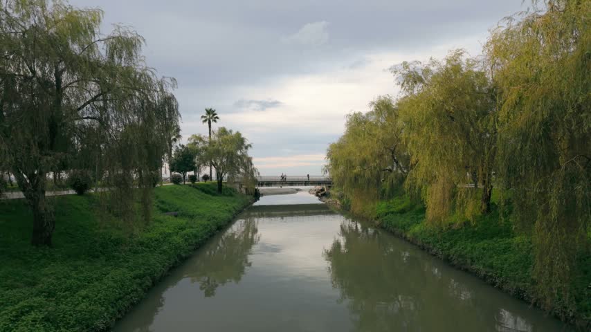 Calm Canal Surrounded by Trees with Pedestrian Bridge