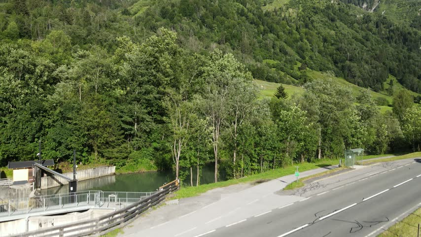 Drone shot of a wooden chalet nestled in green grassy mountain slopes surrounded by forest.