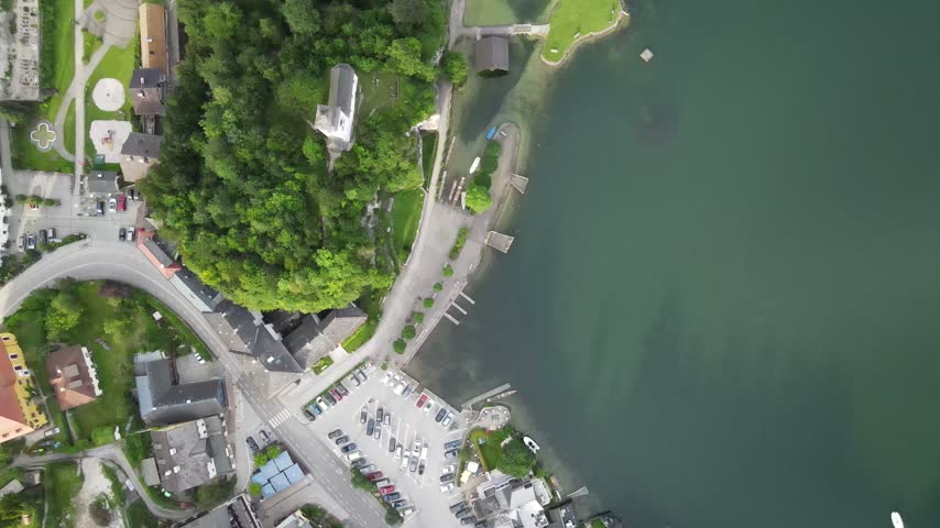 Top down drone view of lake shore, parking lot, and waterfront buildings in Gmunden, Austria.