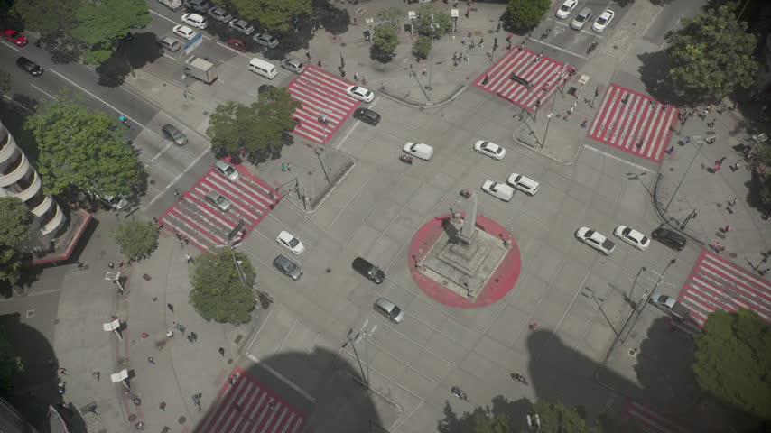 High angle view of traffic and pedestrians at Praca Sete de Setembro, the central square of Belo Horizonte, Minas Gerais, Brazil, with its obelisk and red striped crosswalks on a sunny day.