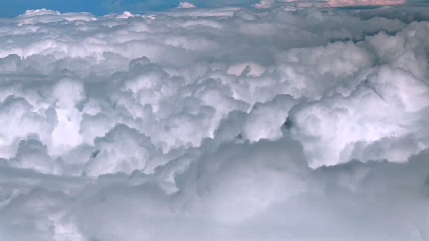 Aerial view of puffy white clouds above a dark landscape