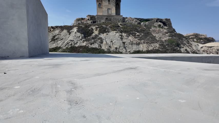 Historic coastal watchtower on a rocky hill under blue sky